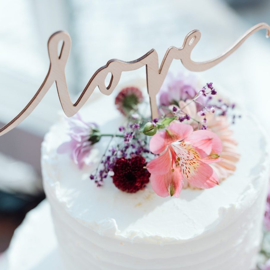Eine elegante Torte mit Blumen und dem Schriftzug "love" aus Holz.