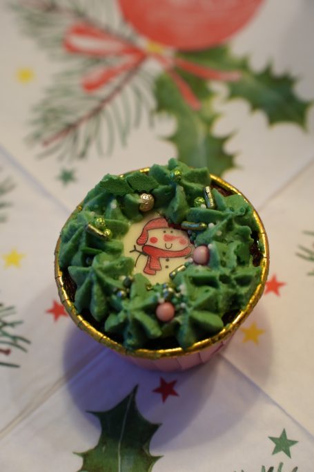 Weihnachtlicher Muffin mit grüner Creme und festlicher Dekoration.