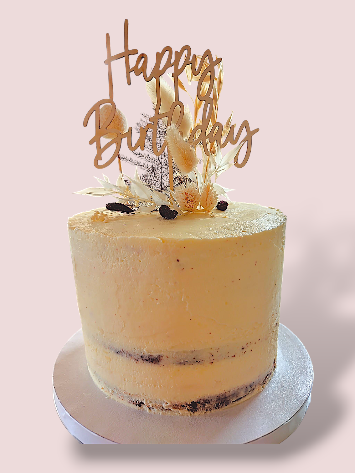 Geburtstagskuchen mit goldener Aufschrift „Happy Birthday“ und dekorativen Toppings.