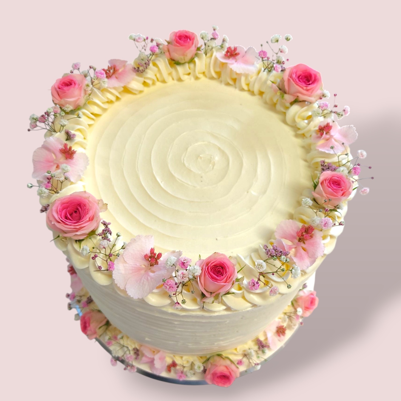 Hochzeitstorte mit zarten Blumenarrangements in Weiß und rosa.