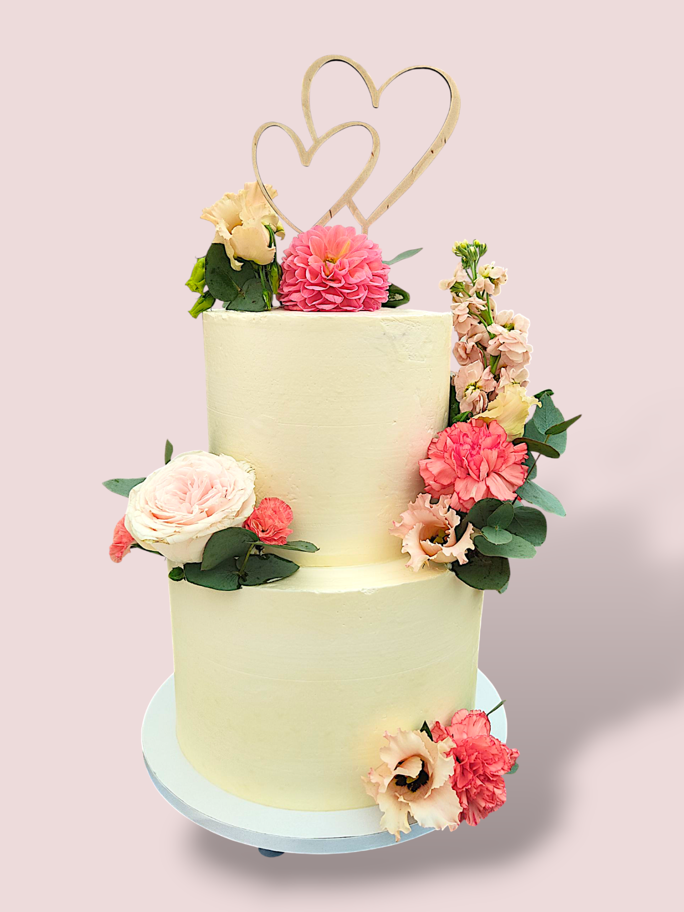 Hochzeitstorte in Weiß mit floralen Dekorationen und Herz-Dekor oben.