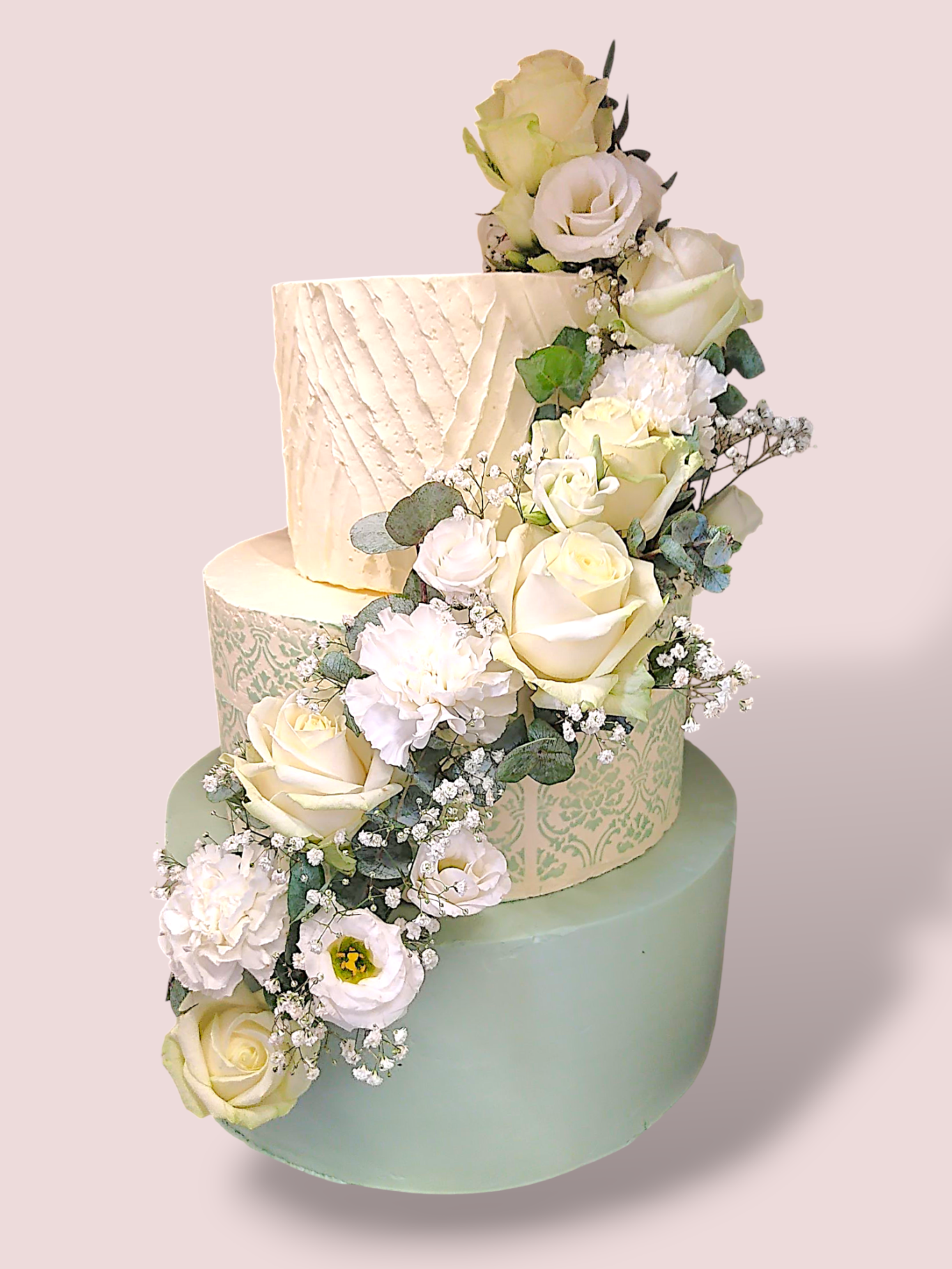 Dreistöckige Hochzeitstorte mit zarten Blumenarrangements in Weiß und Mintgrün.
