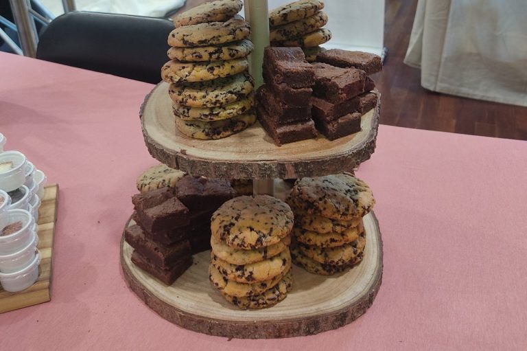 Zwei Etagen mit bunten Keksen und Schokoladenstücken auf einem Holzständer.